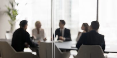 group,of,businesspeople,negotiating,gathered,in,modern,conference,room,,blurred